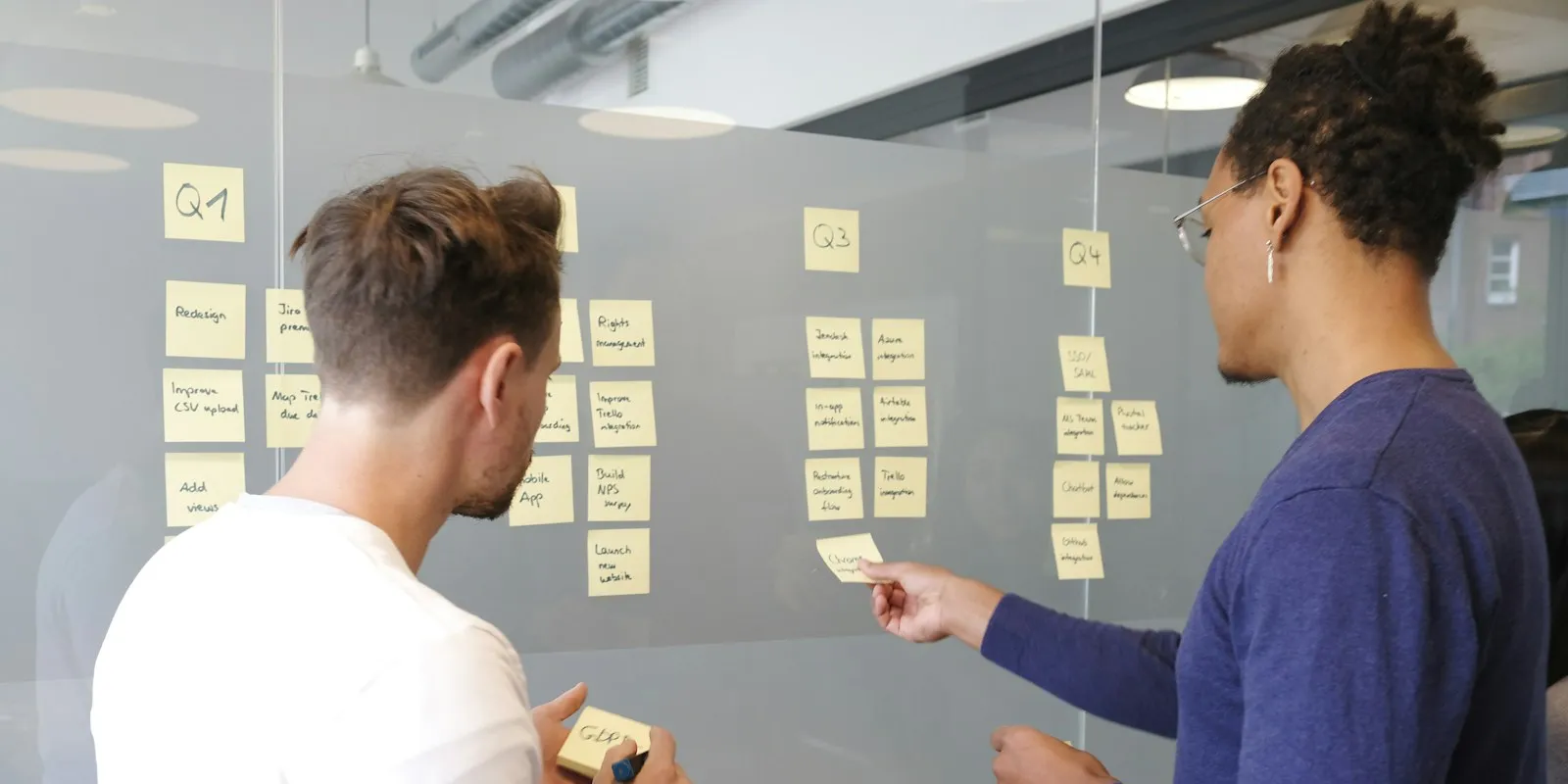 Two people planning a roadmap with sticky notes on a glass wall