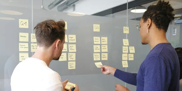 Two people planning a roadmap with sticky notes on a glass wall
