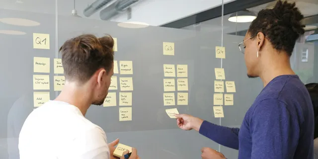 Two people planning a roadmap with sticky notes on a glass wall