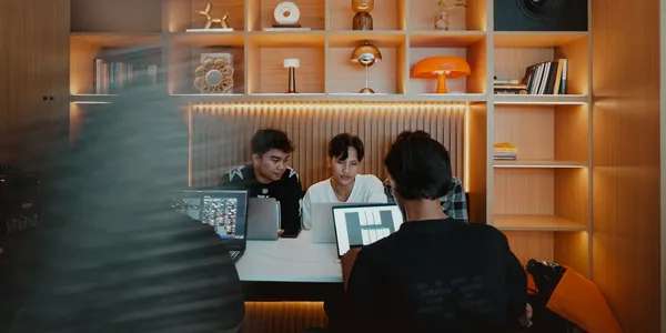 A small team working on laptops in a warm, compact studio