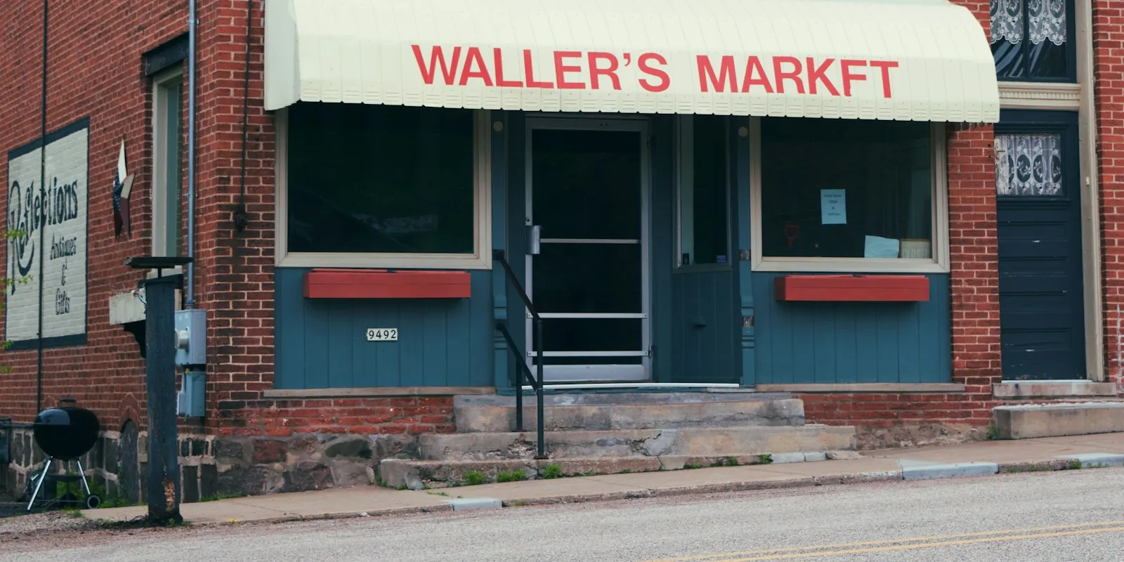 A small brick corner market with a cream awning on a quiet street